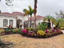 Stunning home exterior featuring vibrant tropical landscaping, palm trees, and a classic red tile roof at 14721 Bowfin Ter, Lakewood Ranch, FL 34202