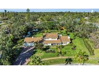 Expansive aerial view of landscaped property featuring a large home, mature trees, and lush green lawn at 7820 Seville Cir, Bradenton, FL 34209