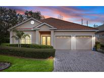 Charming single-story home with a well-manicured lawn, brick driveway and tile roof at sunset at 6211 Skyward Ct, Bradenton, FL 34203