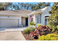 Charming one-story home featuring an attached garage, well-manicured landscaping, and an American flag at 1359 Tearose Pl, Sarasota, FL 34239