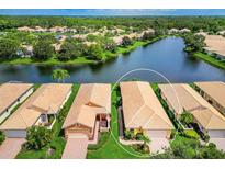 Aerial view of a beautiful single Gathering home with tile roof and lush landscaping on lakefront property at 4244 Reflections Pkwy, Sarasota, FL 34233
