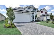 Modern two-story home with a two-car garage and a paved driveway, surrounded by manicured landscaping at 12719 Sunbridge Dr, Venice, FL 34293