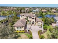 Gorgeous home with a tile roof, lush landscaping, and a brick driveway surrounded by palm trees at 16009 Clearlake Ave, Lakewood Ranch, FL 34202