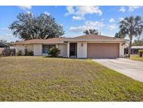 Charming single-story home with a well-maintained lawn, attached garage, and mature trees at 1058 Bounds St, Port Charlotte, FL 33952