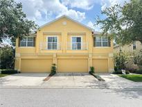 Three unit townhome with yellow exterior, balconies, and matching garage doors at 6768 Breezy Palm Dr, Riverview, FL 33578