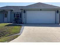 Charming single-story home featuring a two-car garage, lush lawn and mature landscaping at 7076 Nichols St, Englewood, FL 34224