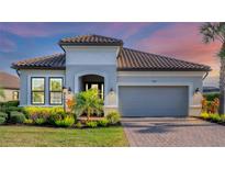 Beautiful single-story home with a gray stucco exterior, tile roof, manicured lawn, and a two-car garage at 4543 Terrazza Ct, Lakewood Ranch, FL 34211