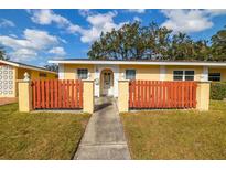 Charming yellow home featuring a well-maintained lawn and a decorative wood fence at 1022 De Soto Dr, Dunedin, FL 34698