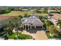 Stunning aerial view of a luxurious home with lush landscaping, a paver driveway, and a tile roof at 12810 Daisy Pl, Bradenton, FL 34212