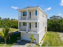 Exterior view of a three-story home featuring a two-car garage and double balconies with white railings at 4207 Marina View Way, Cortez, FL 34215