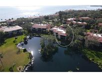 Stunning aerial view of condo complex overlooking lake with water views, lush landscaping, and tile roofs at 6470 Seagull Dr # 311, Bradenton, FL 34210