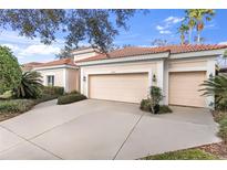 Beige two-car garage door with red tiled roof and lush landscaping at 8717 54Th E Ave, Bradenton, FL 34211