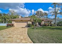 Charming single-story home featuring a brick driveway, attached garage, and well-manicured lawn with tropical landscaping at 4639 Meadowview Cir, Sarasota, FL 34233