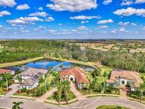 Aerial view showcases the estate's tile roof, circular driveway, meticulous landscaping, and pond views at 16531 Kendleshire Ter, Bradenton, FL 34202