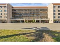 Stunning low-angle shot of a tan five story condo complex with a red tile roof, balconies and well manicured entry at 25188 Marion Ave # E208, Punta Gorda, FL 33950