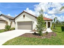 Charming single-story home with a well-manicured lawn and a two-car garage and a red tile roof at 309 Potenza Loop, Nokomis, FL 34275