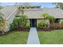 Charming single-story home featuring stone accents, a well-manicured lawn, and lush landscaping at 4931 Hidden Oaks Trl, Sarasota, FL 34232