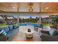 Covered patio with water views, inviting furniture, an outdoor fireplace, and wood plank ceiling at 504 Bayview Dr, Holmes Beach, FL 34217