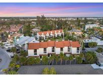 An aerial view showcases a condo complex with a red tile roof surrounded by lush green vegetation at 6790 Sarasea Cir # 6790, Sarasota, FL 34242