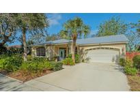 Inviting home featuring a manicured lawn, two-car garage, beautiful landscaping and a cheerful blue front door at 2377 Burton Ln, Sarasota, FL 34239