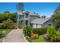 Charming two-story home with a brick driveway, red door, two-car garage and lush landscaping at 501 Reclinata Dr, Longboat Key, FL 34228