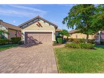 Charming single-story home with a well-manicured lawn and a brick driveway leading to an attached two-car garage at 5556 Cantucci St, Nokomis, FL 34275