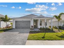 Charming single-story home with a gray driveway, attached garage, and landscaped front yard under a sunny sky at 8071 Slipway Dr, Sarasota, FL 34240