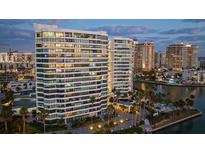 Stunning waterfront condominium with palm trees, lush landscaping, and resort-style amenities at dusk at 888 Blvd Of The Arts # 1008, Sarasota, FL 34236