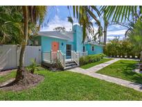 Charming home with a well-manicured lawn, palm trees and quaint walkway leading to a peach colored front door at 115 24Th W St, Bradenton, FL 34205