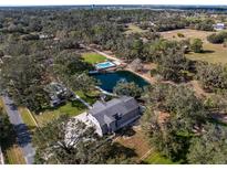 Expansive property featuring a house, private pond, pool, and lush greenery from an aerial perspective at 1228 Wagon Wheel Dr, Sarasota, FL 34240