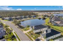 Beautiful aerial view of a neighborhood featuring a pond and well-maintained landscaping under a blue sky at 3831 Creekside Park Dr, Parrish, FL 34219