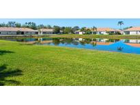Scenic view of a tranquil pond reflecting nearby homes, surrounded by a lush green lawn at 4155 Cascade Falls Dr, Sarasota, FL 34243