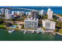 Stunning aerial view of waterfront condos, boat docks, pool, and scenic bridge at 650 Golden Gate Pt # 403, Sarasota, FL 34236