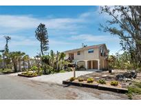 Beautiful home with a sandy driveway and well-manicured landscaping with a red front door and covered parking at 650 Penfield St, Longboat Key, FL 34228