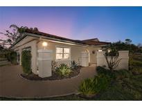 Charming single-story home featuring a red tile roof, stucco walls, and attractive landscaping at twilight at 7340 Golf Pointe Cir, Sarasota, FL 34243