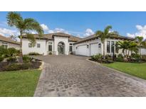 Beautiful one-story home featuring a paver driveway, well-manicured lawn and tropical landscaping at 14803 Derna Ter, Bradenton, FL 34211