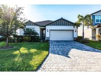 Charming single-Gathering home featuring a manicured lawn and a paver driveway leading to a two-car garage at 3802 Savanna Palms Ct, Bradenton, FL 34211