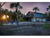Beautiful exterior of a two-story home with a lush tropical landscape, accented by palm trees and an outdoor seating area at 5250 Calle De Rio, Sarasota, FL 34242
