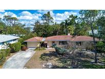 Charming single-story home with a terracotta tile roof and lush tropical landscaping at 1555 Flower Dr, Sarasota, FL 34239