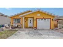 Charming one-story home with a bright yellow exterior, manicured lawn, stamped concrete driveway and cozy front porch at 2416 Webber St, Sarasota, FL 34239