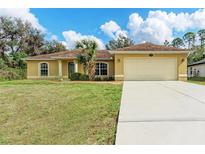 Charming single-story home with a well-manicured lawn and two-car garage and beautiful landscaping at 2720 Dode Ave, North Port, FL 34288