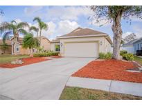Charming single-story home featuring a manicured lawn, palm trees, and a spacious two-car garage at 7113 52Nd E Dr, Bradenton, FL 34203