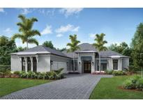 Beautiful single-story home with manicured lawn, palm trees, gray brick driveway, and attached two car garage at 1509 4Th E St, Palmetto, FL 34221