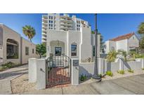 Charming white stucco home with a gated entrance, a brick pathway, and lush landscaping at 422 Burns Ct, Sarasota, FL 34236