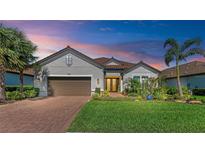 Charming single-story home featuring a well-manicured lawn, mature landscaping, and a brick driveway at 15209 Montello Way, Bradenton, FL 34211