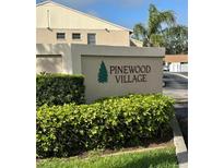 Pinewood Village community sign amidst lush greenery and landscaping at 2607 Woodgate Ln # K9, Sarasota, FL 34231
