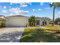 Charming single-story home with a well-maintained lawn and a two-car garage, lush trees on a sunny day at 4202 Donnington Dr, Parrish, FL 34219