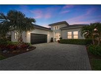 Beautiful home exterior featuring a paver driveway, manicured landscaping, and a dark garage door at 5074 Surfside Cir, Bradenton, FL 34211