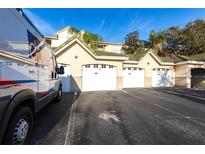 Exterior view of garages with green roofs and a service vehicle parked in front under a bright blue sky at 5122 Northridge Rd # 110, Sarasota, FL 34238