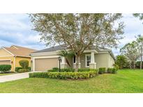 Attractive single-level home boasting lush green landscaping, a large tree, and an attached two-car garage at 3839 Autumn Fern Ter, Sarasota, FL 34243